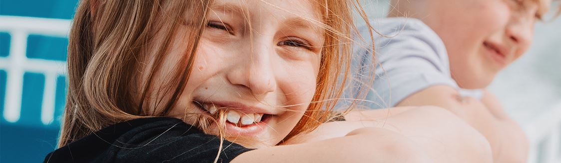En flicka står vid relingen på en skärgårdsbåt och ler mot kameran.