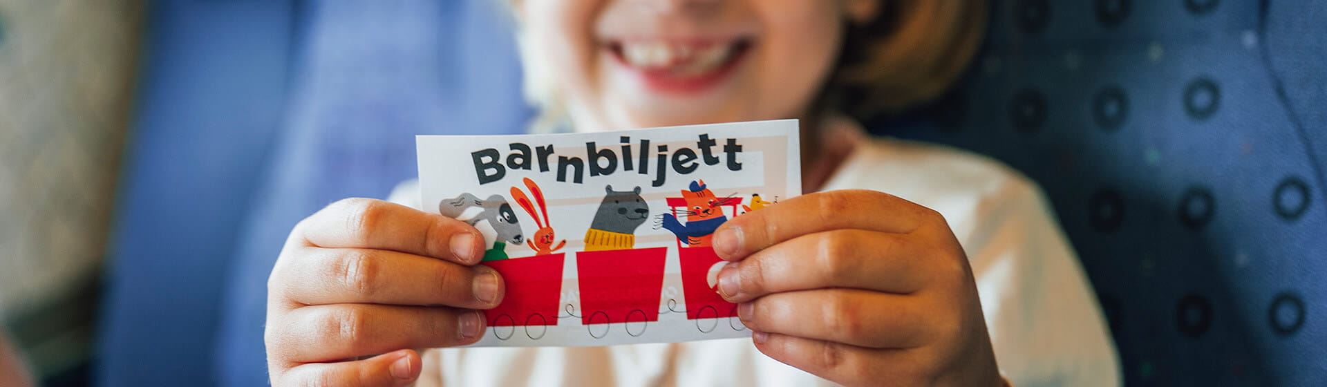 Ett barn håller upp en biljett med ordet "barnbiljett" på.