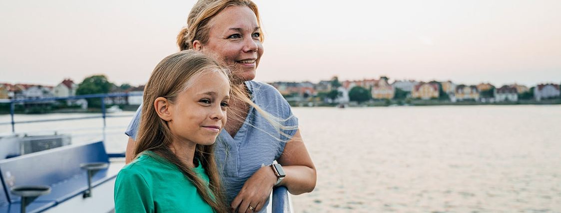 En mamma och en flicka står vid relingen ombord på en skärgårdsbåt.