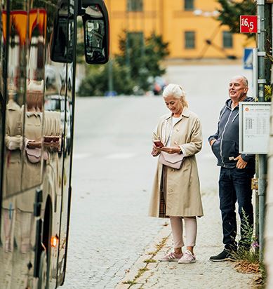 Resenärer väntar på bussen vid hållplats.