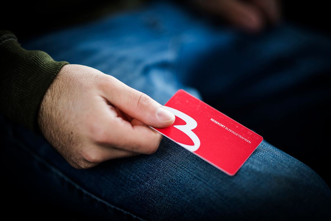 En hand håller i ett gammalt, rött resekort.